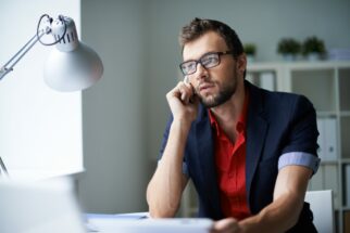 Handsome businessman in smart casual and eyeglasses speaking on the phone in office